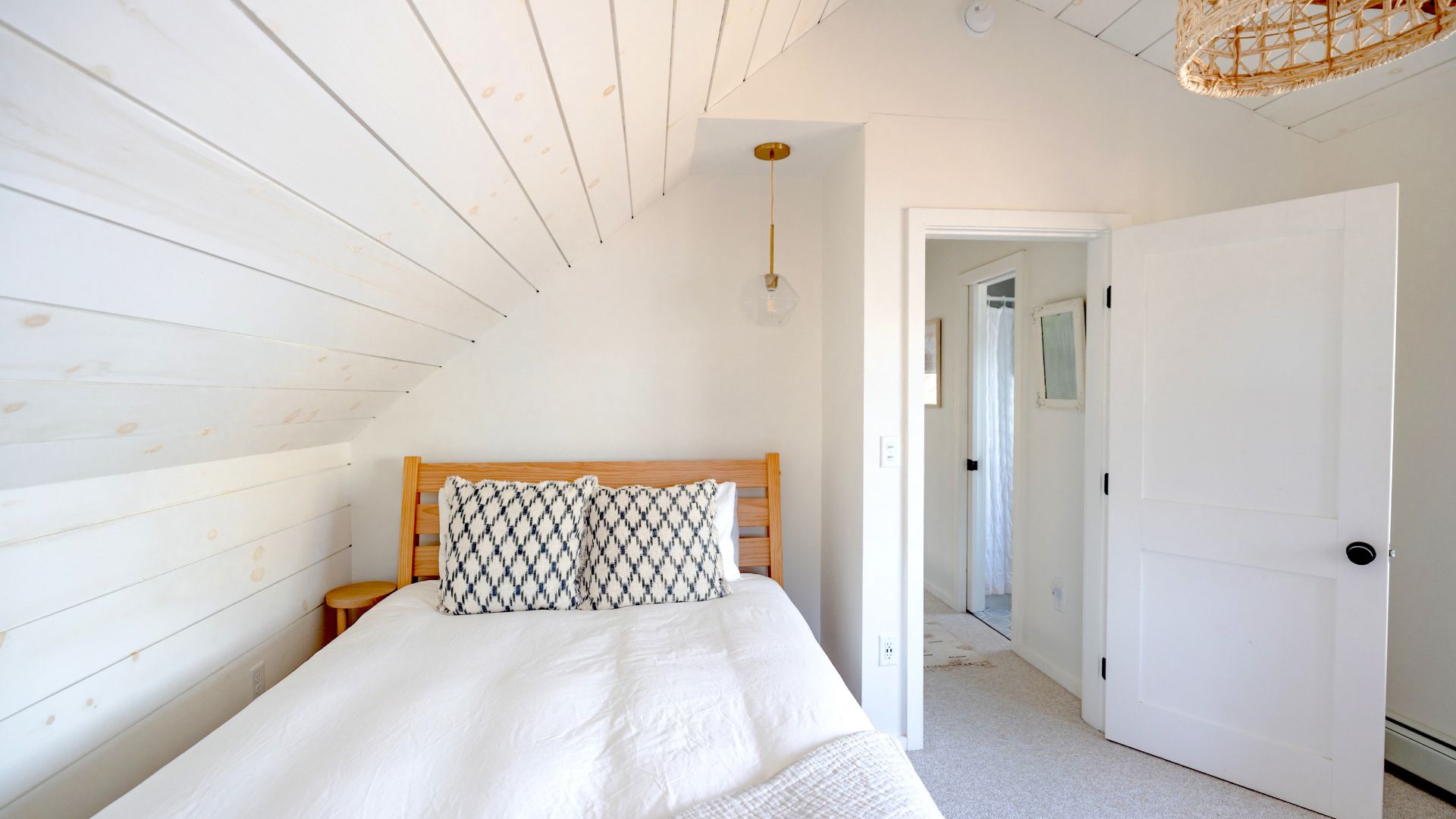 A bedroom with white walls and a wooden headboard