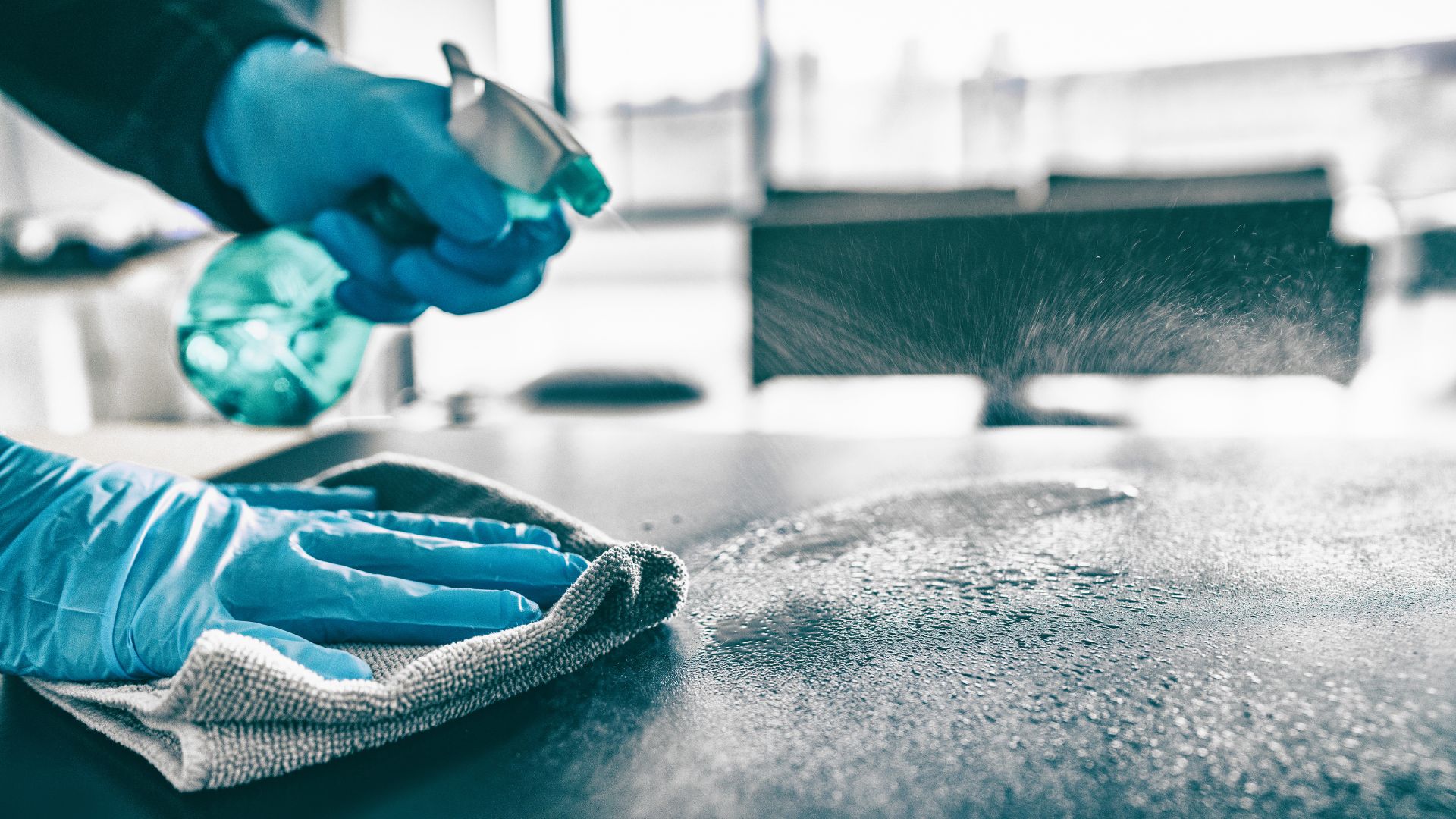 A person in blue gloves and blue gloves cleaning a table